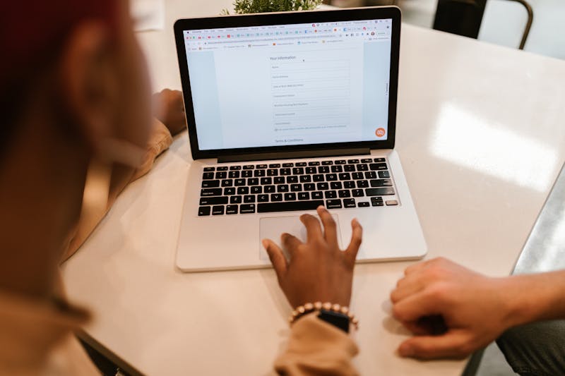 Due persone che compilano insieme un modulo online su un laptop