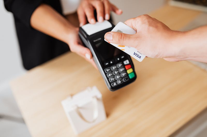 Mani che effettuano un pagamento contactless con carta di credito su un terminale POS