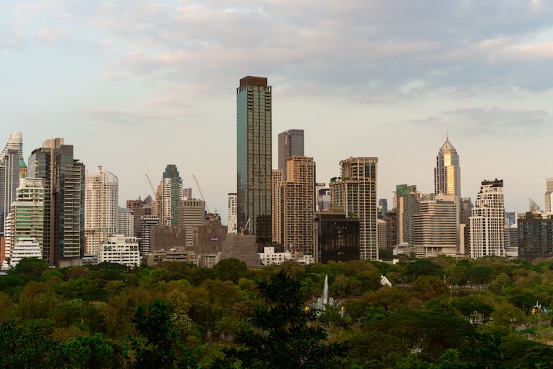Panorama dello skyline di Bangkok al tramonto con grattacieli moderni e vegetazione tropicale